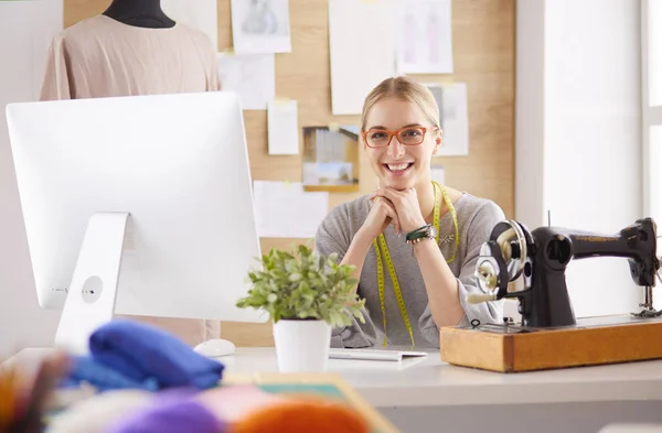 Beautiful young girl in a factory with a sewing machine at the table — Stock Photo, Image