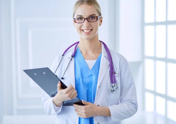 Médecin souriante avec un dossier en uniforme debout — Photo