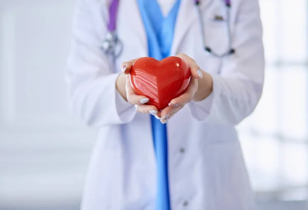 Kobieta lekarz z stetoskop trzyma serce w ramionach. Koncepcja medyczna i Kardiologiczna w medycynie — Zdjęcie stockowe