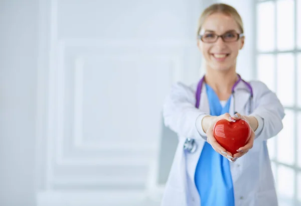 Female doctor with stethoscope holding heart in her arms. Healthcare and cardiology concept in medicine — Stock Photo, Image