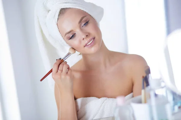 Uma foto de uma jovem mulher aplicando pó facial no banheiro — Fotografia de Stock