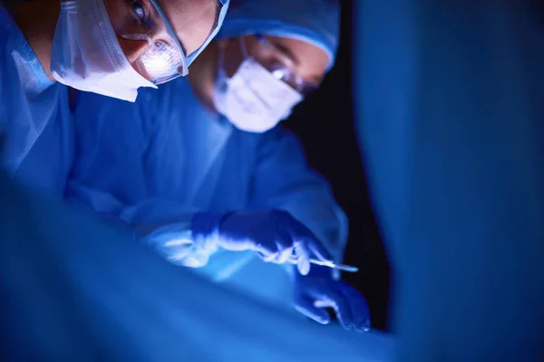 Doctors team in surgery in a dark background. — Stock Photo, Image