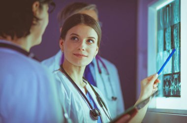 Bir grup doktor bir klinikte röntgenleri inceliyor, teşhis koymayı düşünüyorlar.