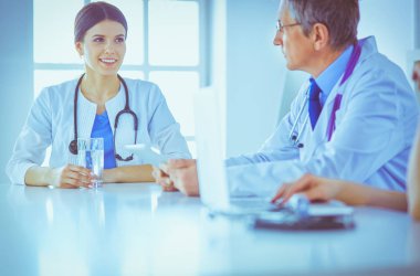 Parlak bir hastane odasında meslektaşlarıyla çalışan gülümseyen bir doktor.