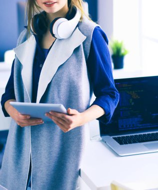 Ofis masasında çalışan ve dizüstü bilgisayarla yazan kendine güvenen genç bir iş kadını.