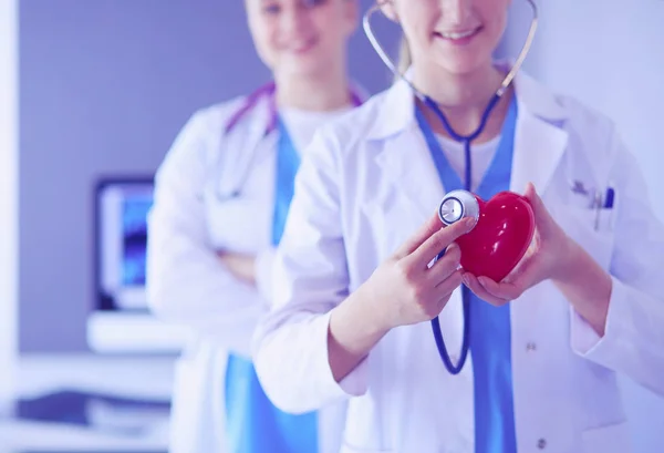 Обрезанная съемка двух молодых врачей женского пола со стетоскопом, держащим сердце. — стоковое фото