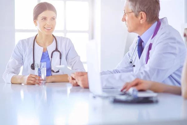 Médecin souriant utilisant un ordinateur portable travaillant avec ses collègues dans une chambre d'hôpital lumineuse — Photo