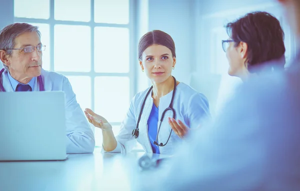 Équipe médicale sérieuse utilisant un ordinateur portable dans une salle de consultation lumineuse — Photo