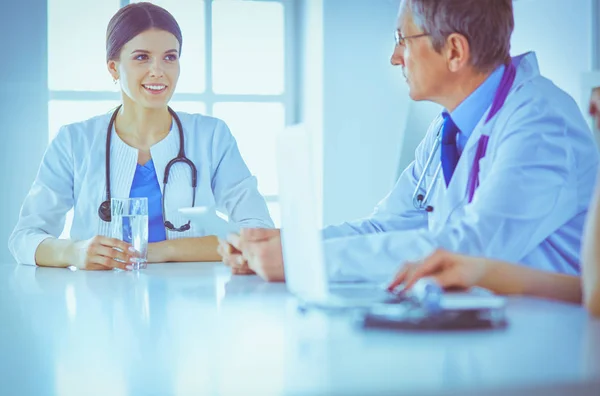 Lächelnde Ärztin mit einem Laptop, die mit ihren Kollegen in einem hellen Krankenhauszimmer arbeitet — Stockfoto