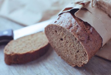 Tahta masanın üzerinde kağıda sarılı bir somun ekmek..