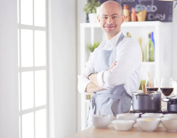 Handsome man is cooking on kitchen and smiling