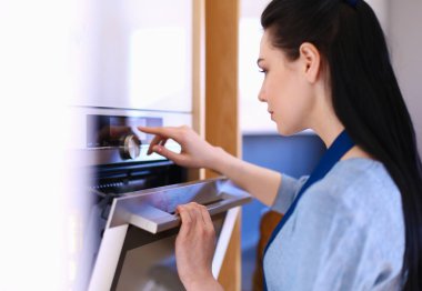 Güzel genç bayan pastasının fırında ne yaptığını kontrol ediyor.