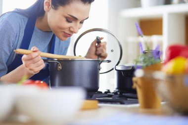 Mutfakta ahşap kaşıkla yemek pişiren kadın