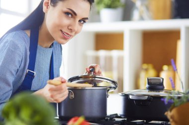 Mutfakta ahşap kaşıkla yemek pişiren kadın