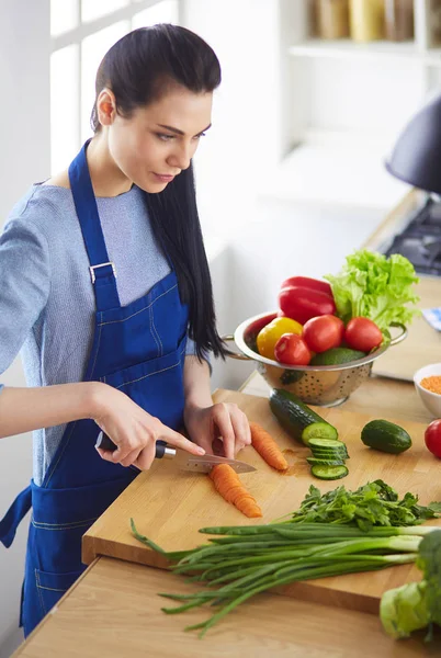 Mutfakta sebze doğrayan genç bir kadın.