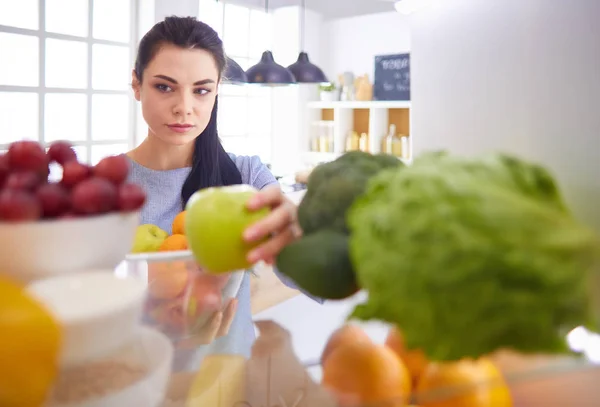 Glimlachende vrouw die een vers fruit uit de koelkast haalt, gezond voedsel concept — Stockfoto