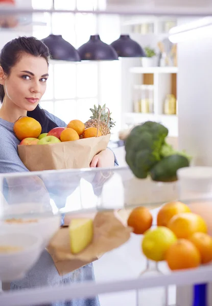 Smiling woman taking a fresh fruit out of the fridge, healthy food concept — Stock Photo, Image