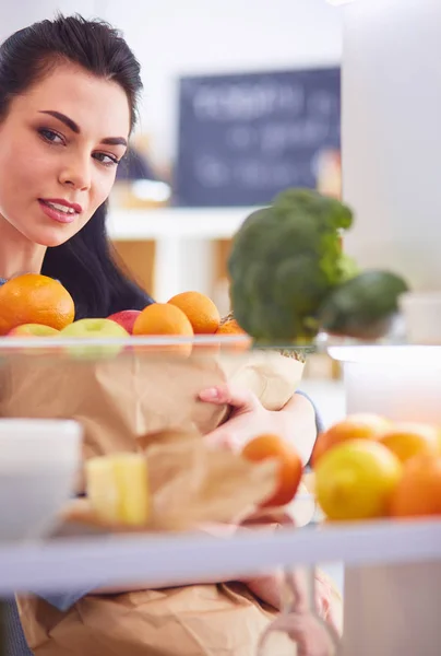Usmívající se žena vytahuje čerstvé ovoce z ledničky, zdravý stravovací koncept — Stock fotografie