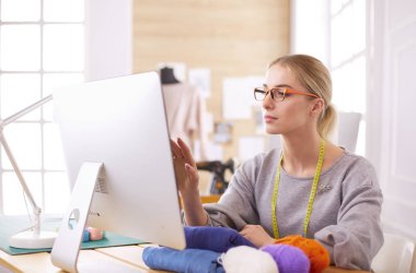 Atölyedeki kadın tasarımcı bilgisayar ekranına bakıyor