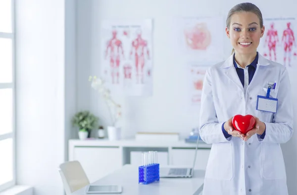 Un médecin avec stéthoscope examinant le cœur rouge, isolé sur fond blanc — Photo