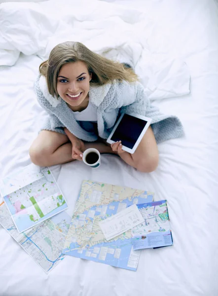 Entspannte junge Frau sitzt mit einer Tasse Kaffee und digitalem Tablet im Bett — Stockfoto