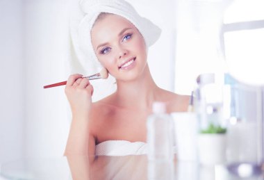 Genç bir kadının banyoya yüz pudrası sürerken fotoğrafı.