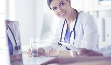Parlak bir hastane odasında meslektaşlarıyla çalışan gülümseyen bir doktor.