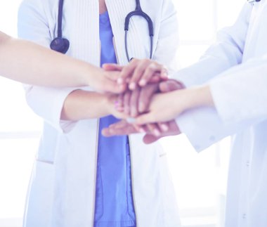 Bir grup doktor ellerini birleştiriyor. Yakın plan.