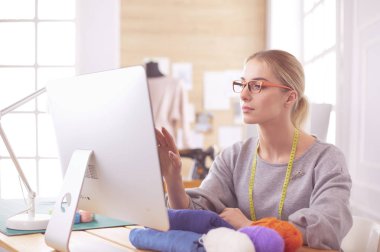 Atölyedeki kadın tasarımcı bilgisayar ekranına bakıyor