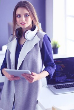 Ofis masasında çalışan ve dizüstü bilgisayarla yazan kendine güvenen genç bir iş kadını.