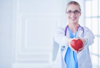 Stetoskoplu kadın doktor kollarında kalp tutuyor. Tıpta sağlık ve kardiyoloji kavramı