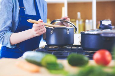 Mutfakta ahşap kaşıkla yemek pişiren kadın