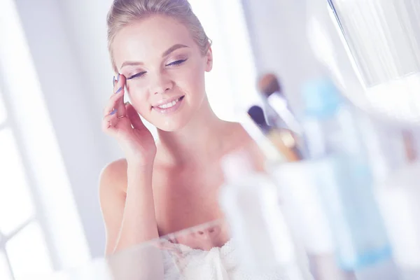 穿着浴衣的年轻女人看着浴室的镜子 — 图库照片