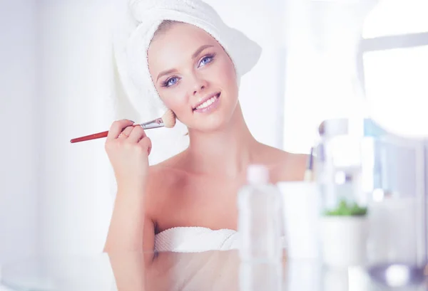 Ein Bild einer jungen Frau, die im Badezimmer Gesichtspuder aufträgt — Stockfoto