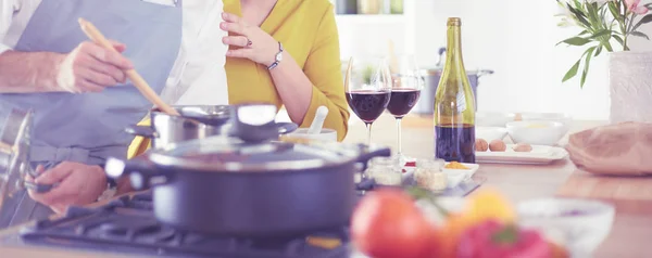Atractiva pareja enamorada de cocinar y abre el vino en la cocina mientras cocinan la cena para una velada romántica — Foto de Stock