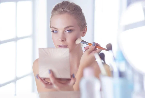 A picture of a young woman applying face powder in the bathroom — Stock Photo, Image