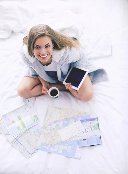 Entspannte junge Frau sitzt mit einer Tasse Kaffee und digitalem Tablet im Bett — Stockfoto