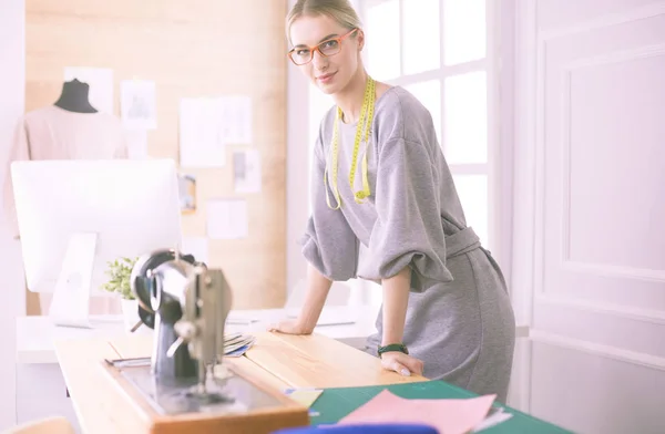 Створення нових модних стилів. Весела молода жінка шиє, сидячи на робочому місці в майстерні моди — стокове фото