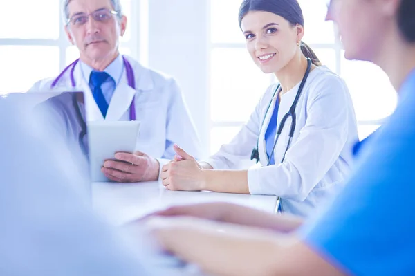 Equipo médico serio discutiendo casos de pacientes en un consultorio luminoso — Foto de Stock