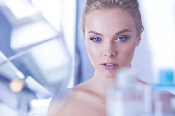 Young woman in bathrobe looking in bathroom mirror — Stock Photo, Image