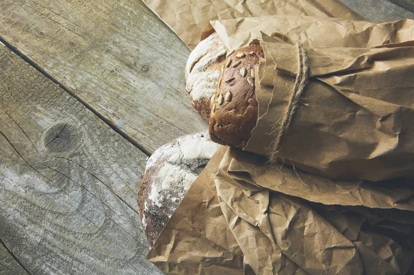 Vers gebakken brood rustieke broden in papieren zakken op donkere hout achtergrond — Stockfoto