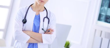 Doktor muayenehanesinde steteskopla gülümseyen genç bayan doktor.