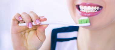 Genç ve güzel bir kız diş fırçasıyla ağız sağlığını koruyor..