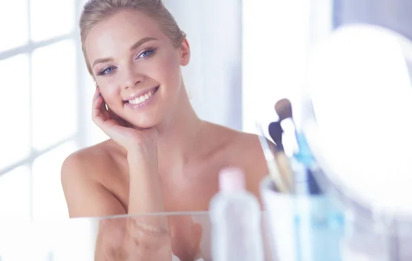 Jonge vrouw in badjas op zoek in badkamer spiegel — Stockfoto