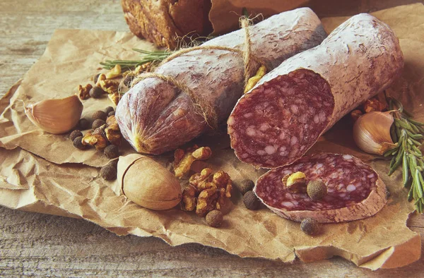 Französische Salami und Walnüsse auf Bastelpapier auf Holzgrund — Stockfoto