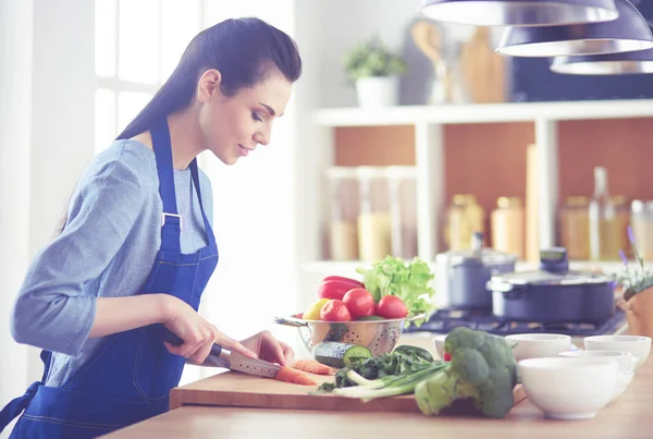 Junge Frau schneidet Gemüse in Küche zu Hause — Stockfoto