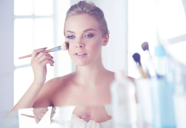 Una foto di una giovane donna che applica polvere per il viso in bagno — Foto Stock