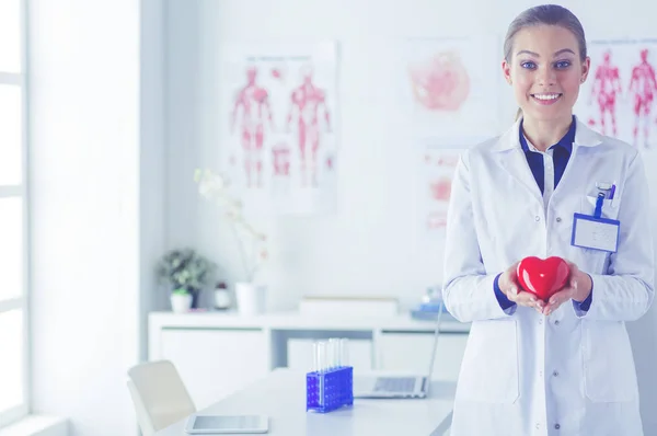 Um médico com estetoscópio examinando coração vermelho, isolado em fundo branco — Fotografia de Stock