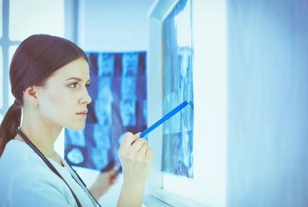 Jeune femme médecin souriante avec stéthoscope pointant vers la radiographie au cabinet des médecins — Photo