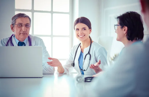 Equipo médico serio utilizando un ordenador portátil en una sala de consulta luminosa —  Fotos de Stock